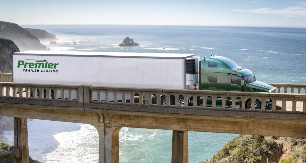 Premier truck driving across a bridge overlooking the ocean