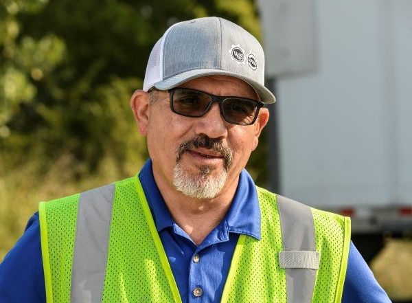 Happy Premier employee standing in front of a Premier truck